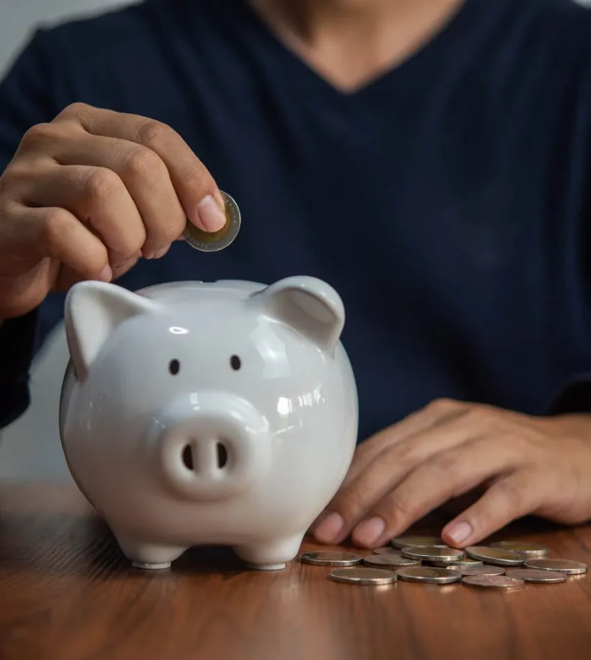 Money saving concept man holds coins and drops into a piggy bank. Business Finance, Banking and Investment Tax Accounting | Safeguard Estate and Financial Planning